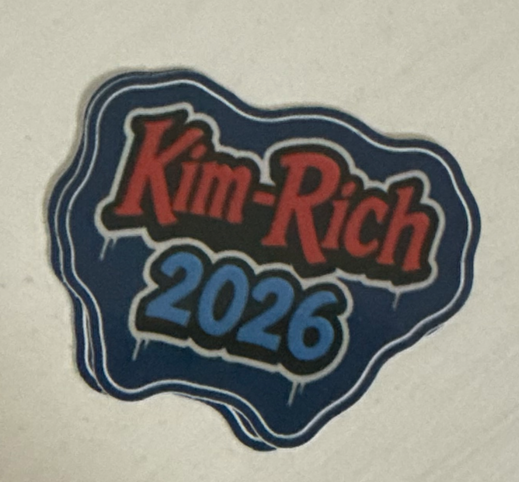 Our original 2026 travel sticker, with red Kim-Rich lettering and a blue year on a dark navy background.